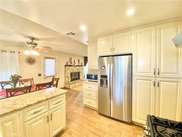 kitchen featuring light wood finished floors, visible vents, appliances with stainless steel finishes, open floor plan, and light stone countertops