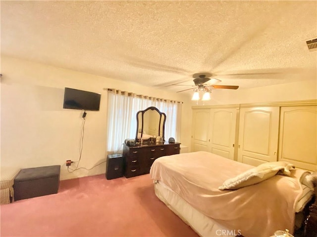 bedroom featuring light carpet, ceiling fan, a textured ceiling, and a closet