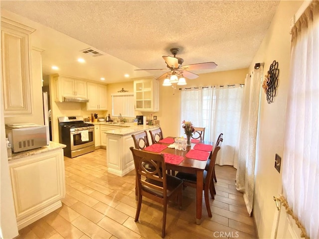 dining room with ceiling fan, visible vents, light wood-style flooring, and a textured ceiling