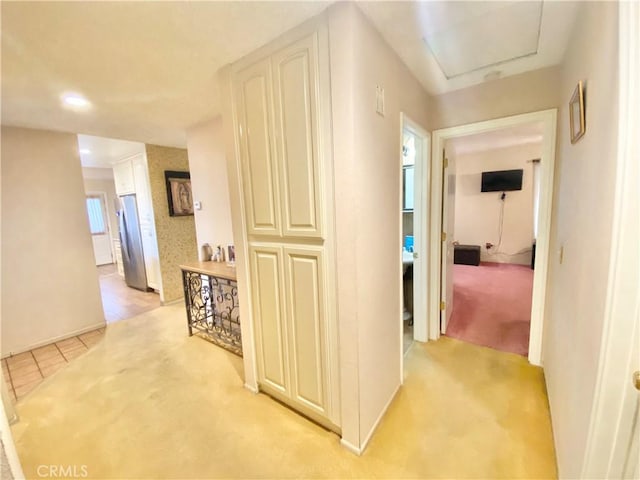 hall with light tile patterned floors and light colored carpet