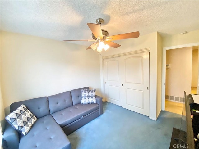 carpeted living room with a textured ceiling and a ceiling fan