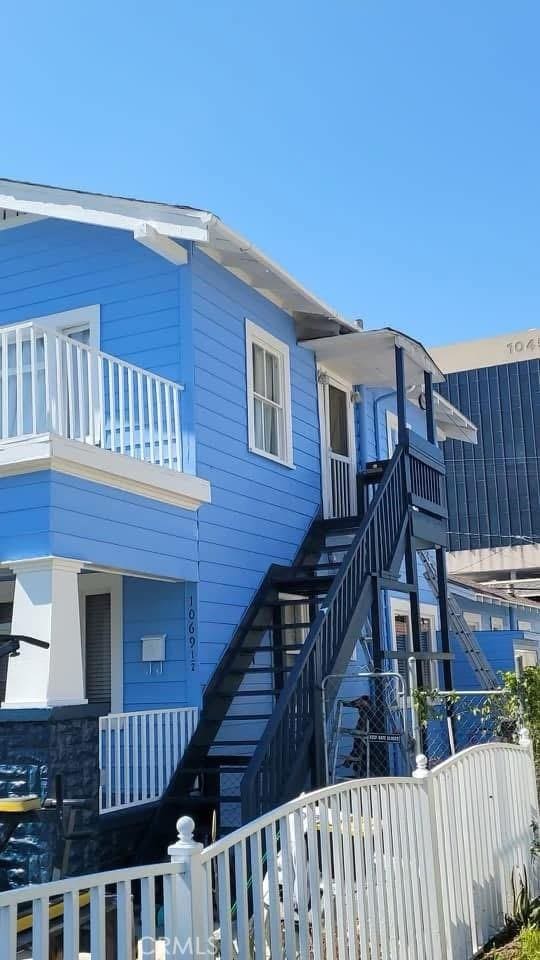 view of front of house with a balcony, fence, and stairway