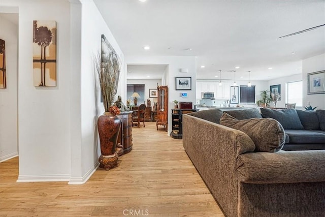 living area featuring baseboards, recessed lighting, and light wood-style floors