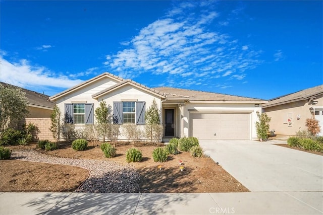 view of front of property with a garage, concrete driveway, a tile roof, and stucco siding