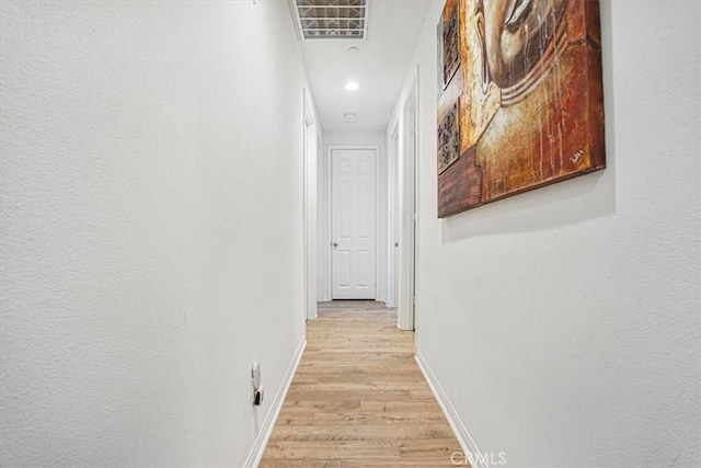 corridor with light wood-style floors and baseboards