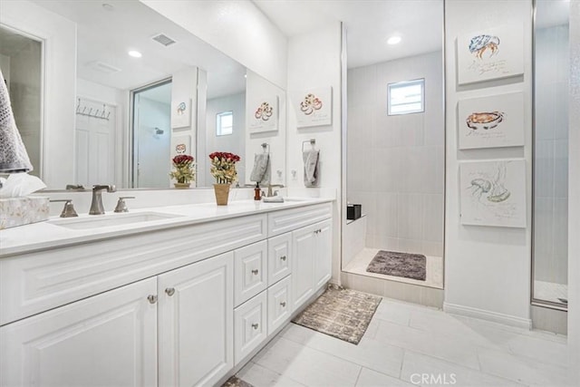 bathroom with a sink, visible vents, tiled shower, tile patterned floors, and double vanity