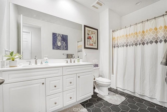 full bath featuring visible vents, double vanity, a sink, and toilet