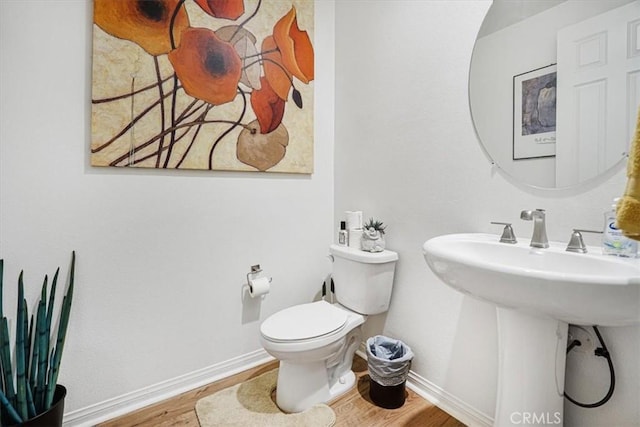 bathroom with wood finished floors, toilet, and baseboards