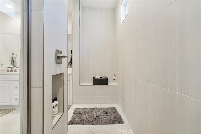 full bath with tile patterned flooring, a tile shower, and vanity