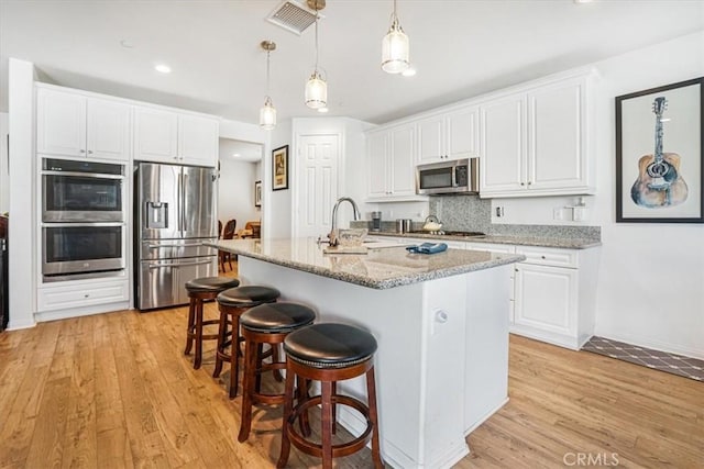 kitchen with appliances with stainless steel finishes, light stone countertops, and white cabinets