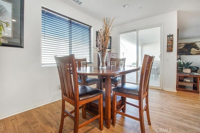 dining area with visible vents, light wood-style flooring, and baseboards