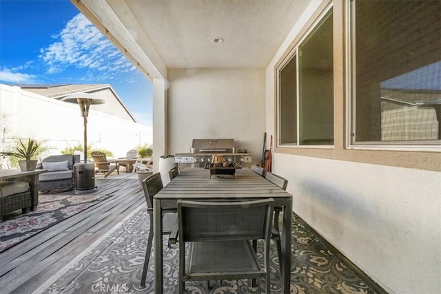 deck featuring outdoor dining space, a fenced backyard, and a grill