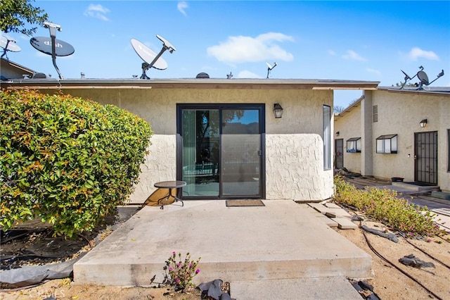 entrance to property featuring a patio and stucco siding