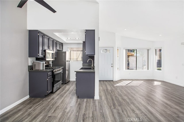 kitchen with dark wood-style flooring, dark countertops, appliances with stainless steel finishes, open floor plan, and baseboards