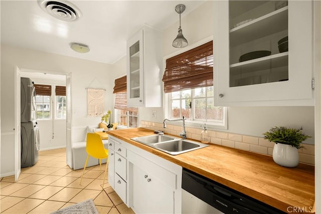 kitchen with visible vents, stacked washer and dryer, white cabinets, and wood counters