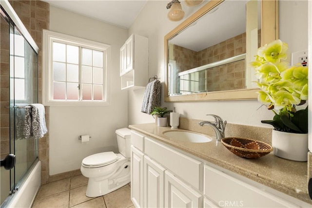 bathroom featuring tile patterned flooring, baseboards, toilet, enclosed tub / shower combo, and vanity