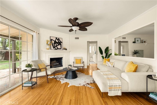 living room featuring a fireplace, wood finished floors, visible vents, and a ceiling fan