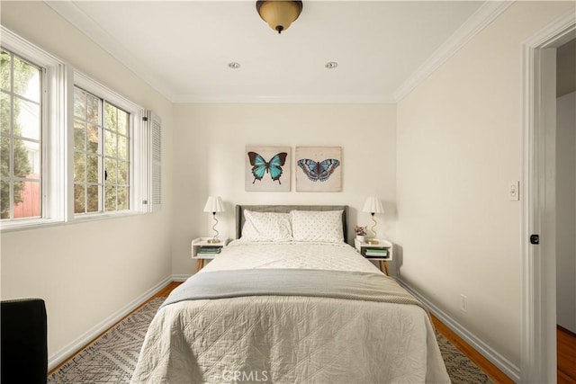 bedroom featuring baseboards, wood finished floors, and crown molding