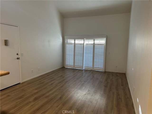 spare room featuring dark wood-style flooring and baseboards