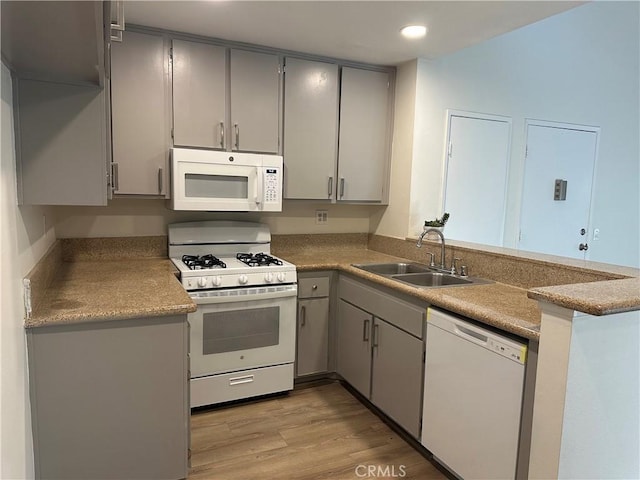 kitchen featuring white appliances, a sink, and gray cabinetry