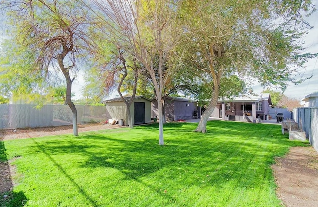 view of yard with a storage shed, a fenced backyard, and an outdoor structure