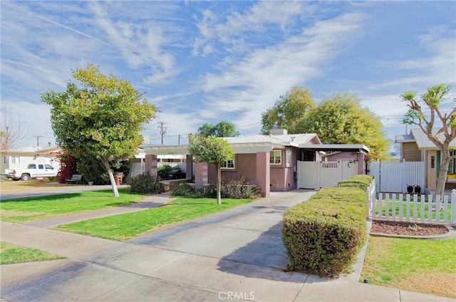 view of front of property with concrete driveway, a front yard, fence, and stucco siding