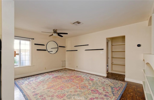 unfurnished room featuring ceiling fan, dark wood-style flooring, visible vents, and baseboards