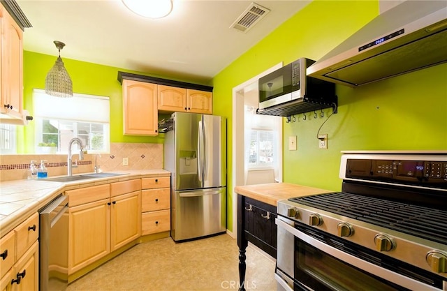 kitchen with decorative light fixtures, stainless steel appliances, visible vents, a sink, and under cabinet range hood