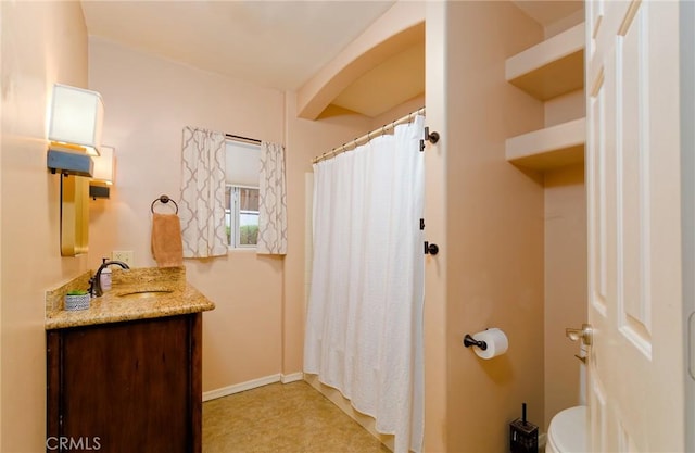 bathroom featuring toilet, baseboards, and vanity