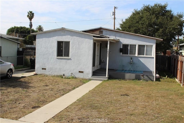 bungalow-style house featuring crawl space, fence, a front lawn, and stucco siding