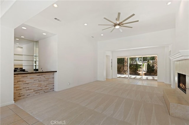 unfurnished living room featuring recessed lighting, light carpet, a fireplace, and light tile patterned floors