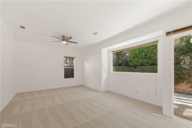 empty room featuring light carpet, visible vents, and a ceiling fan