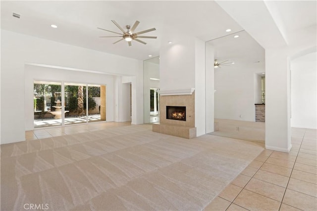 unfurnished living room featuring light tile patterned floors, recessed lighting, light carpet, a fireplace, and a ceiling fan