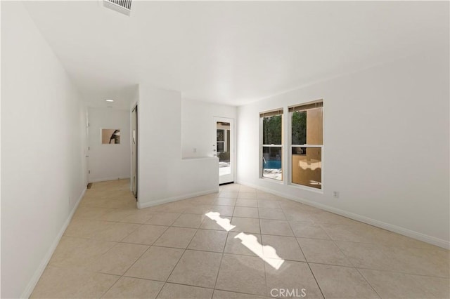 empty room featuring light tile patterned floors, visible vents, and baseboards