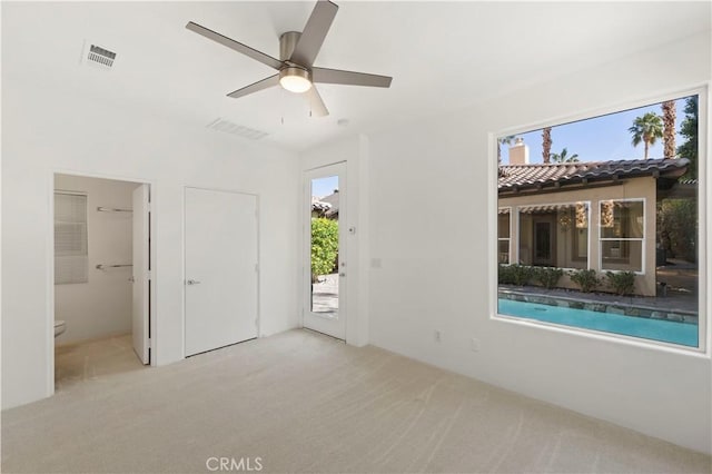 interior space with light carpet, ceiling fan, and visible vents