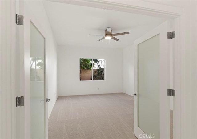 spare room with ceiling fan and light colored carpet