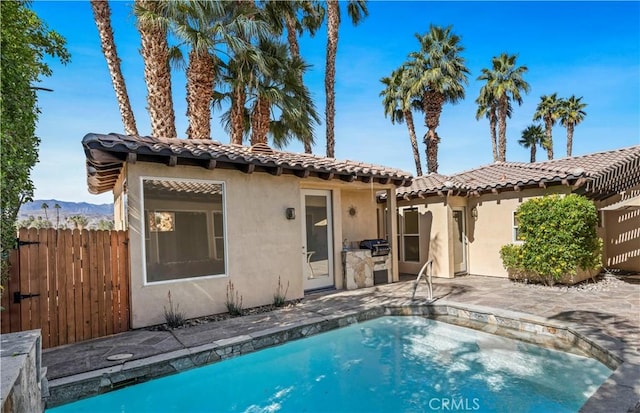 back of property featuring a patio, fence, a tiled roof, a fenced in pool, and stucco siding