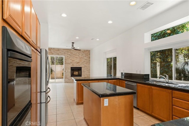 kitchen with stainless steel appliances, a wealth of natural light, a large fireplace, and a kitchen island