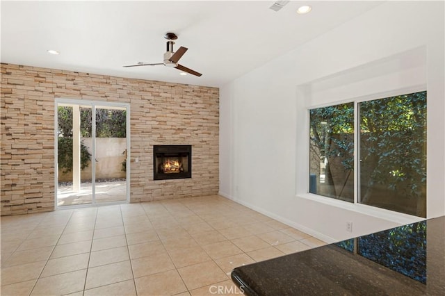 unfurnished living room with plenty of natural light, a fireplace, light tile patterned flooring, and a ceiling fan