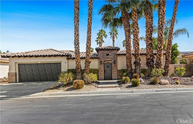 mediterranean / spanish-style house with a garage, stone siding, driveway, and stucco siding