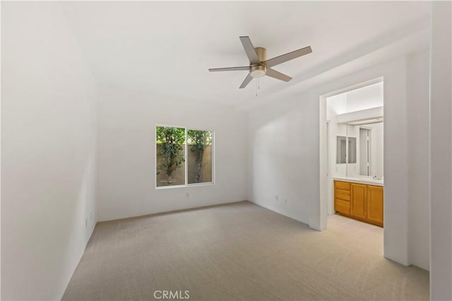 unfurnished bedroom with ensuite bath, a sink, and light colored carpet