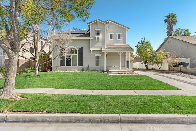 view of front of house with a porch, a front yard, roof mounted solar panels, and driveway