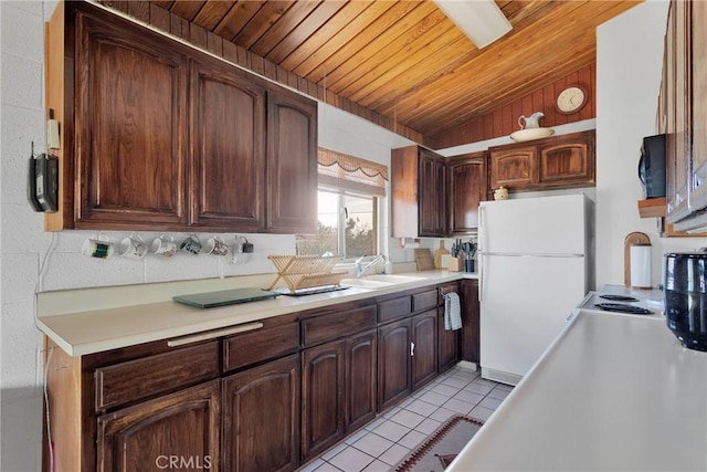 kitchen with light tile patterned flooring, a sink, wood ceiling, light countertops, and freestanding refrigerator