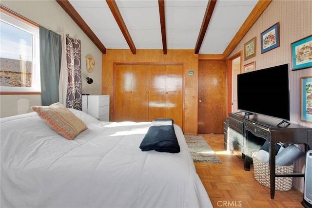 bedroom featuring a closet, lofted ceiling with beams, and wallpapered walls