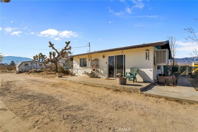 rear view of property with a patio area, fence, a mountain view, and a storage unit