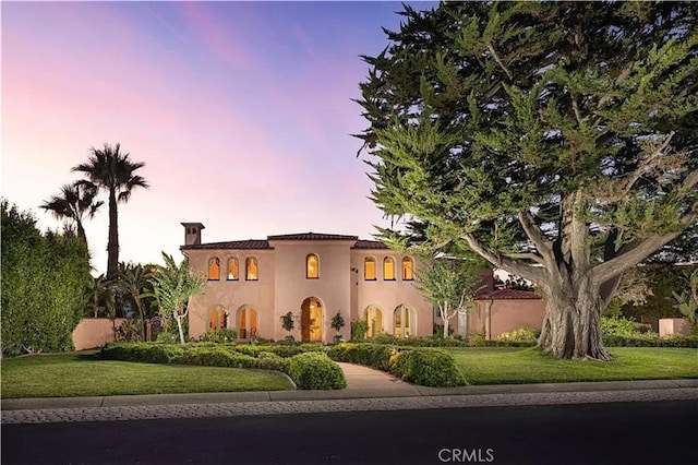 mediterranean / spanish-style house with stucco siding and a yard