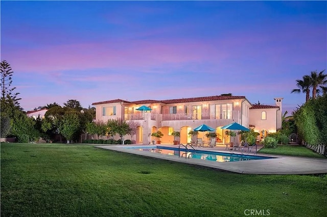 back of property featuring an outdoor pool, a patio, and a yard