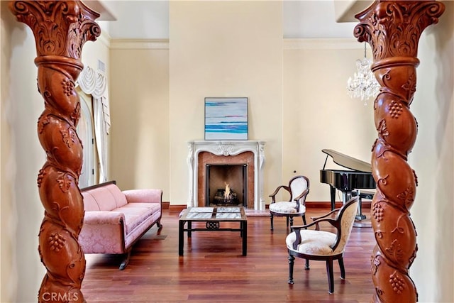 living area featuring crown molding, a premium fireplace, wood finished floors, baseboards, and an inviting chandelier