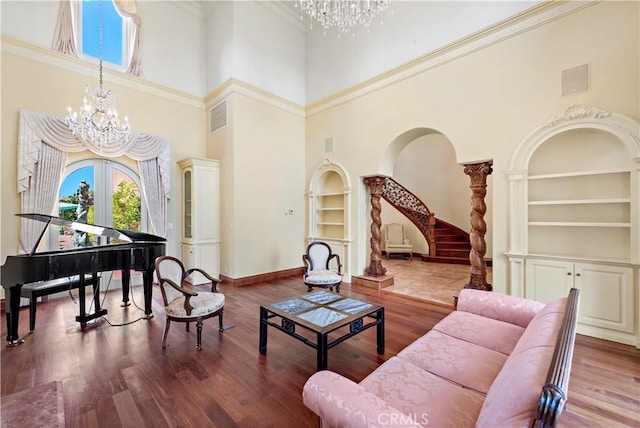 living room with built in shelves, wood finished floors, stairs, french doors, and an inviting chandelier