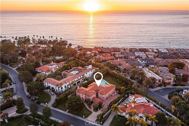 aerial view at dusk with a water view and a residential view